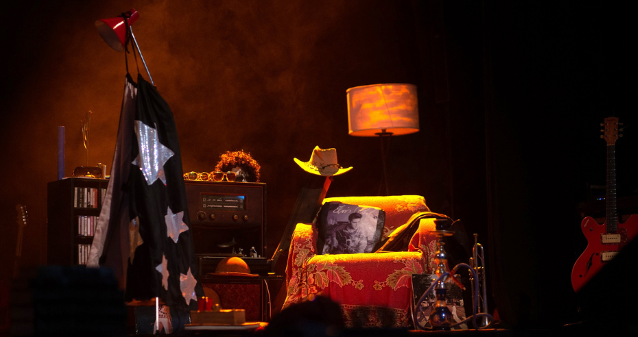 Cenário do musical com poltrona, objetos simbólicos, instrumentos musicais e iluminação aconchegante que representam o escritório criativo de Raul Seixas.