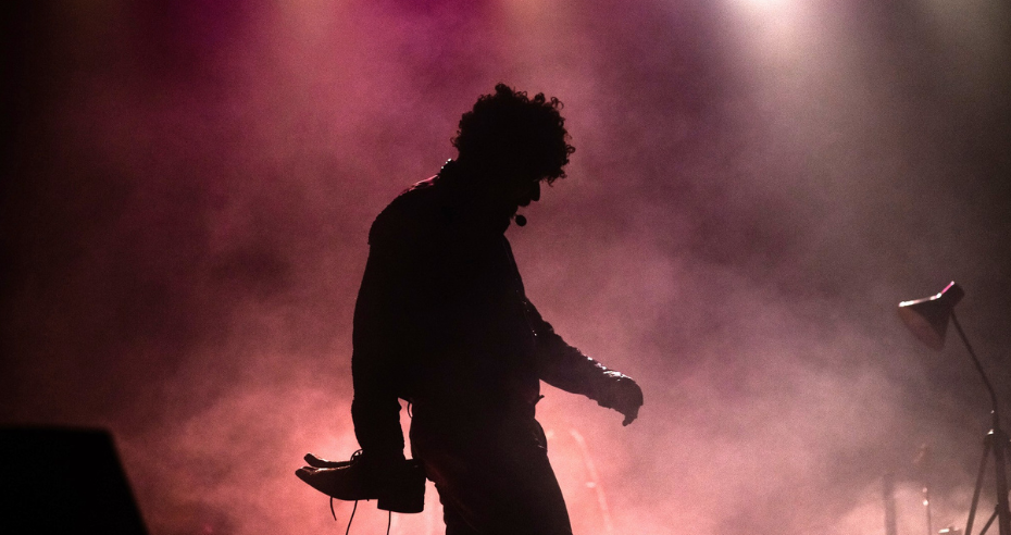 Silhueta do ator em contraluz, envolto em fumaça e luz cênica, representando momentos reflexivos de Raul Seixas no musical.